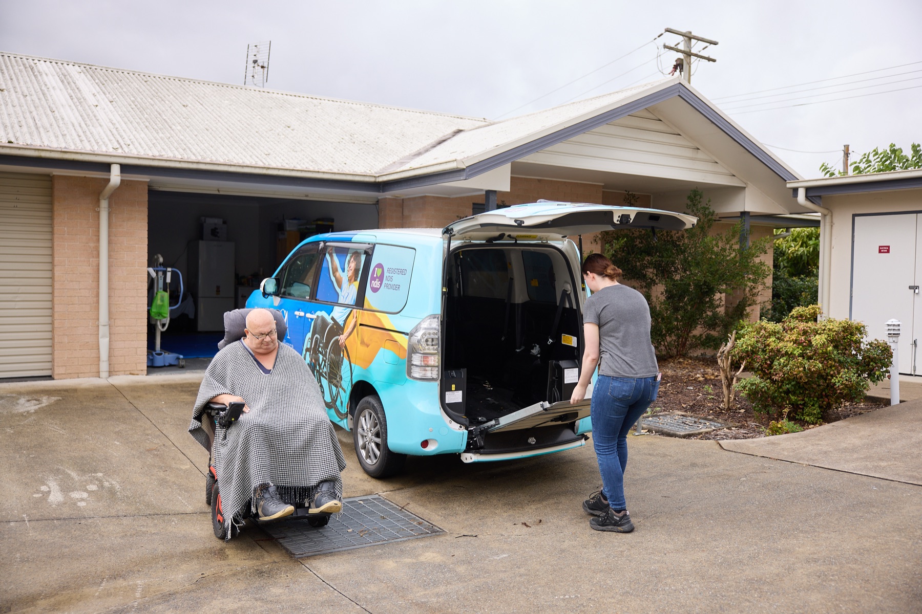 Support worker opening the wheelchair-accessible van for a participant